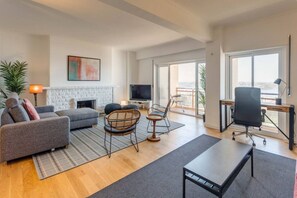 A spacious living room with a fireplace, comfortable seating, a TV, and a balcony with a view. - Ajuda · Belvedere TM Flat With a Magnificent View (Lisboa)