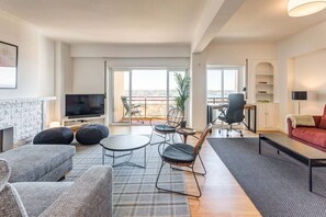 A modern living room with a fireplace, comfortable seating, a flat-screen TV, and a balcony with a view. - Ajuda · Belvedere TM Flat With a Magnificent View (Lisboa)