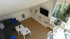 Ein modernes Wohnzimmer mit einem dunkelgrauen Sofa, einem weißen Couchtisch und einem Essbereich mit weißen Stühlen und einem Tisch.