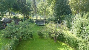 Ein üppiger Garten mit Trampolin, dichtem Grün und einer Holzhütte im Hintergrund.
