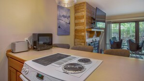 Una cocina con estufa integrada, tostadora y microondas. Una ventana grande ofrece vistas al exterior.