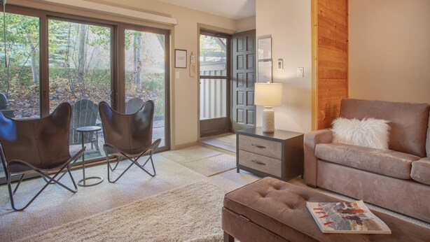 Una sala de estar moderna con un sofá, dos sillones, una lámpara y una revista sobre una mesita de centro.