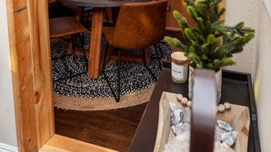 A cozy wooden dining area with a chandelier, a table set for four, and a view of the forest through large windows. - Summer Escape Near Lake Arrowhead Village (Twin Peaks)