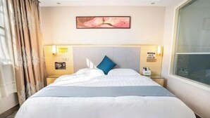 A hotel room with a large bed, a headboard, bedside tables, a nightstand, a window, and a painting on the wall. - Hezhou Xintai Hotel (Hezhou)
