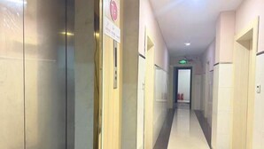 A corridor with a tiled floor, a fire extinguisher, and a door at the end. - Hezhou Xintai Hotel (Hezhou)