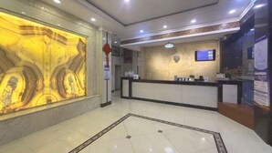 A hotel reception area with a marble wall, a reception desk, and a digital display. - Hezhou Xintai Hotel (Hezhou)