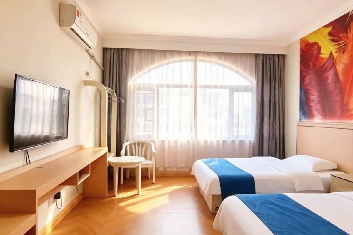 A hotel room with two beds, a TV, a desk, and a chair.
