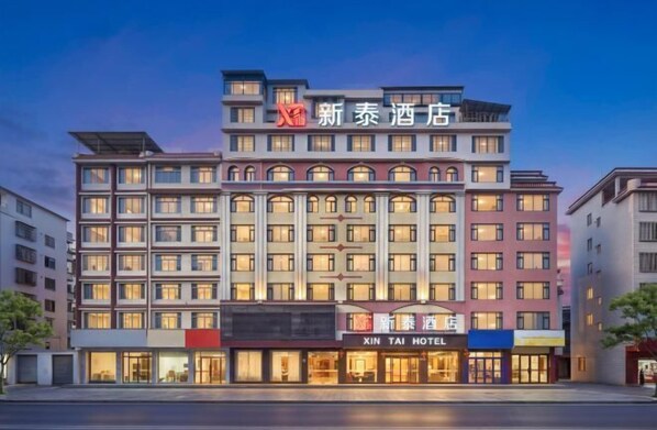 Un hotel de varios pisos con un letrero llamativo que dice 'XIN TAI HOTEL'.