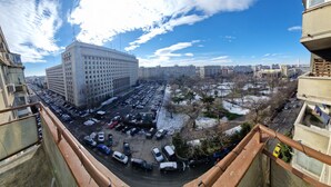 Ein Hochhaus mit Parkplatz darunter.