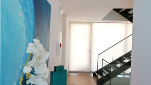 A modern interior with a staircase, a large abstract painting, and a white orchid. - Seaview and private pool - house for 6 (Lourinhã)