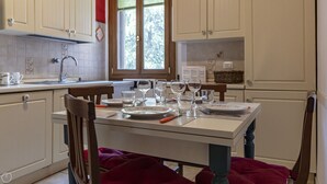 Une cuisine avec des meubles blancs, une fenêtre et une table à manger mise avec des assiettes, des verres et des couverts.
