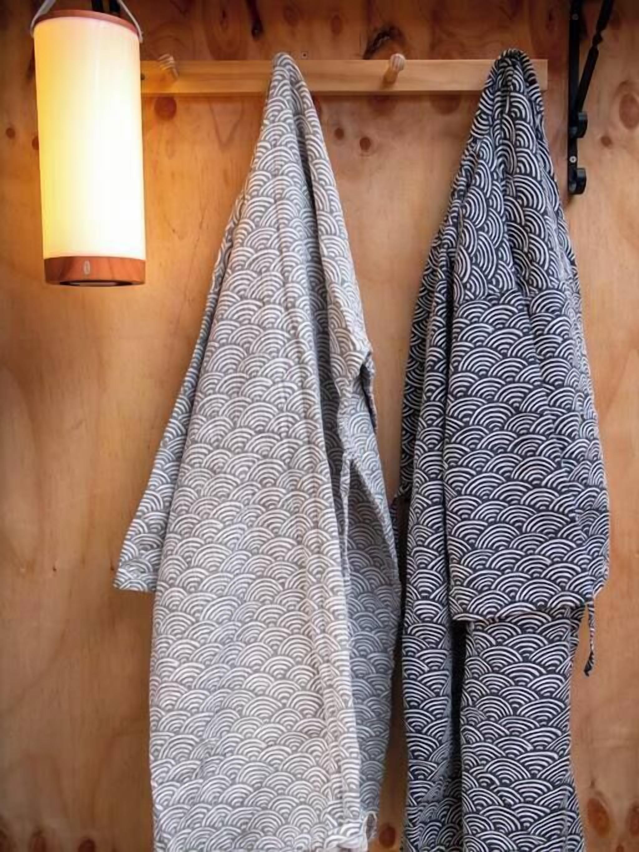 Two patterned blankets hanging on a wooden wall.