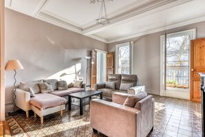 Un salón espacioso con un sofá de color beige, una mesita de centro y un suelo estampado.
