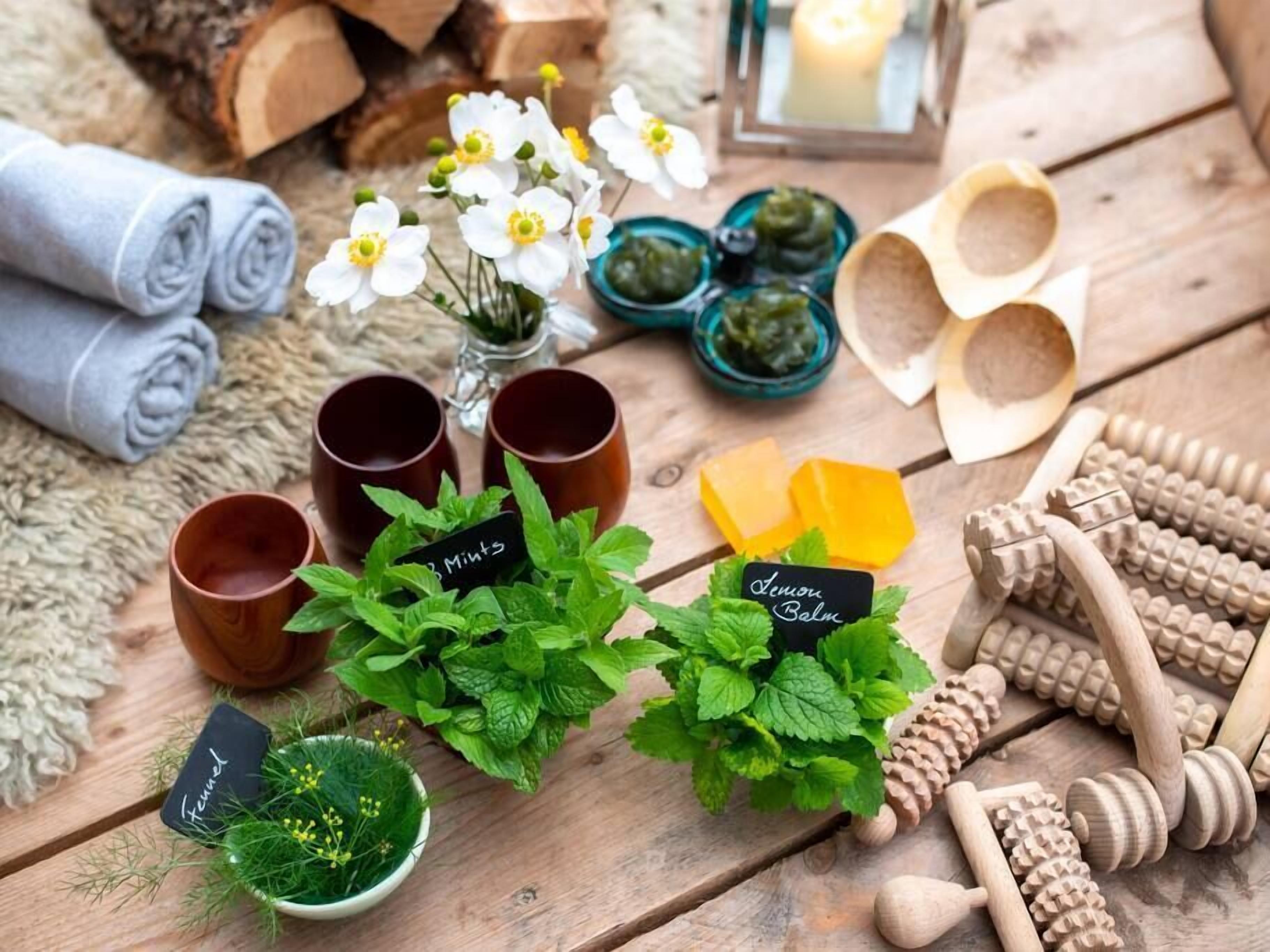 A wooden table with various items including a small potted plant, wooden cups, and a candle.
