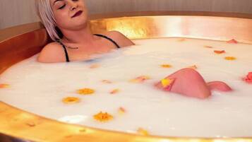 Une personne dans une baignoire, entourée de pétales de rose.