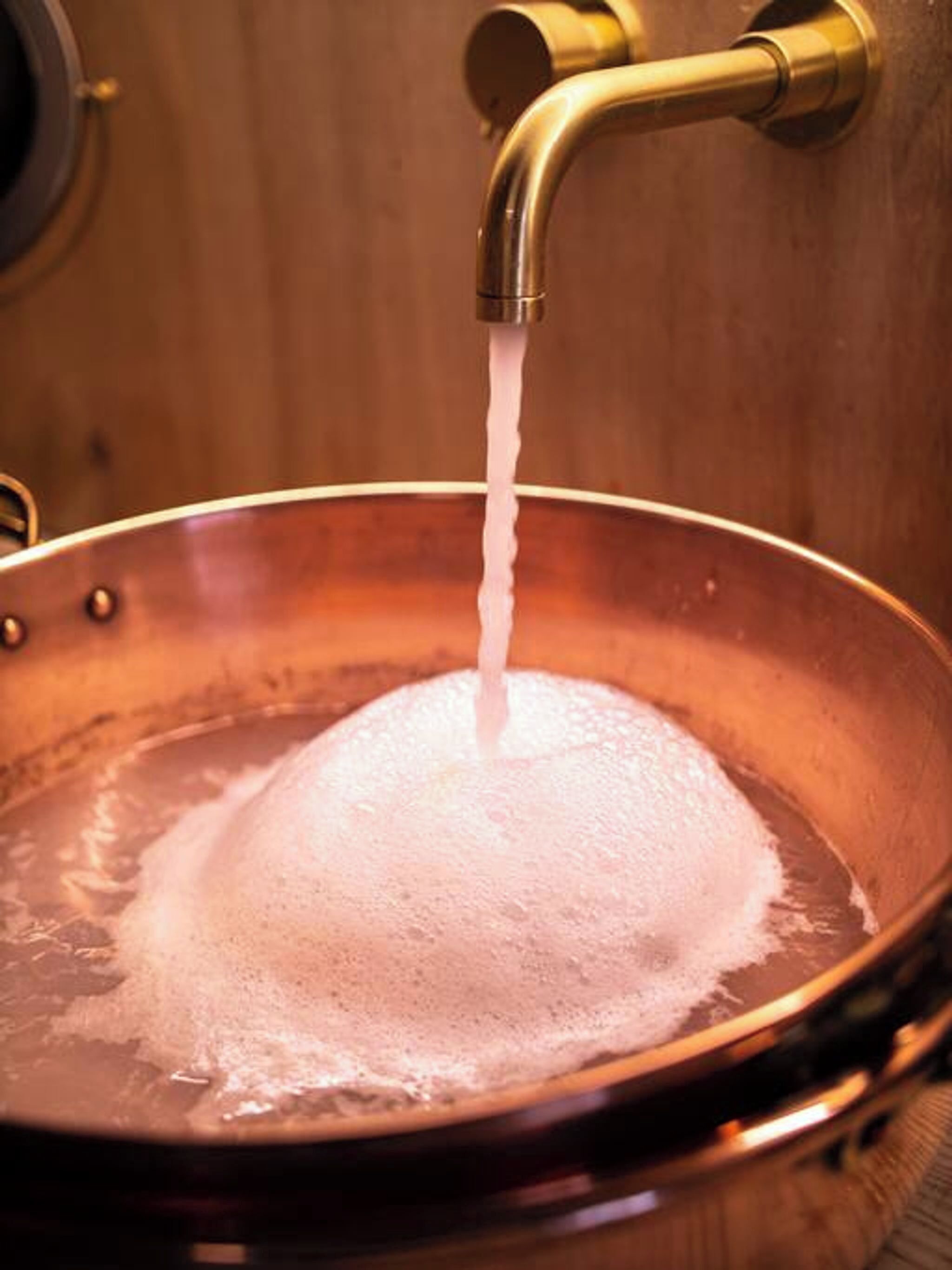 A copper pan with water flowing into it.