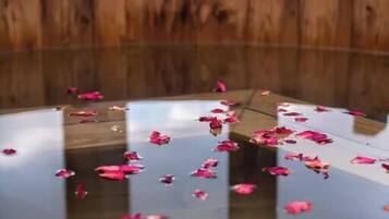 Une structure circulaire en bois, dotée d’une surface réfléchissante et parsemée de pétales roses.