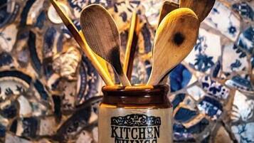 A kitchen with a decorative tile backsplash and a jar labeled "KITCHEN THINGS" containing wooden utensils.