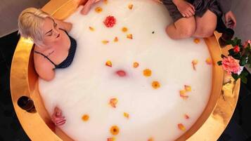 A bathtub filled with white liquid and flower petals, surrounded by a golden frame.