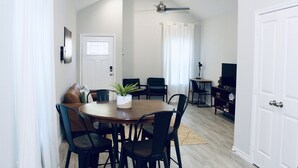 A dining area with a round table, black chairs, a potted plant, and a ceiling fan. - The Beaver Den 30 day stays King bed Lake Conroe (Montgomery)