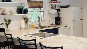 A modern kitchen with a central island, bar stools, a refrigerator, and a coffee machine. - Completely renovated lakehouse with all the extras (Warsaw)