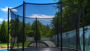 Ein Trampolin mit Sicherheitsnetz im Garten.