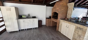 A kitchen with a brick oven, a microwave, and a coffee maker on a wooden cabinet.