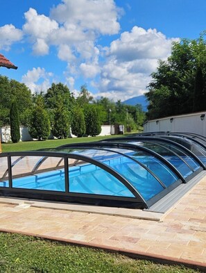 A swimming pool with a glass enclosure, surrounded by a brick patio and greenery. - Avrigelli, Kids&family Friendly (Avrig)