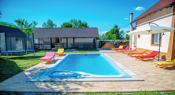 A swimming pool with lounge chairs, a covered seating area, and a building with a tiled roof. - Avrigelli, Kids&family Friendly (Avrig)