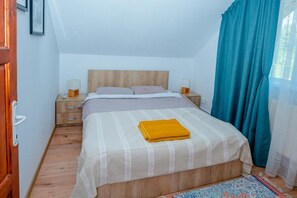 A bedroom with a bed, nightstands, a wooden headboard, a window with curtains, and a door. - Avrigelli, Kids&family Friendly (Avrig)