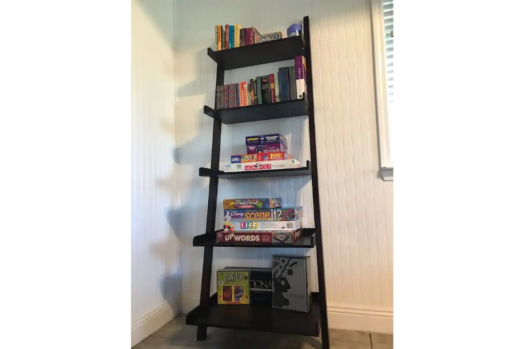 Une bibliothèque noire contenant divers jeux de société et livres.