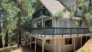 A two-story house with a balcony, surrounded by trees.