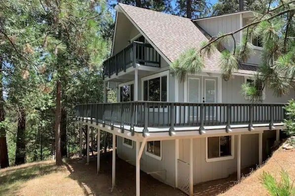 A two-story house with a balcony, surrounded by trees.