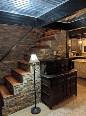 Stairs lead to an upper level, with a dark cabinet below.