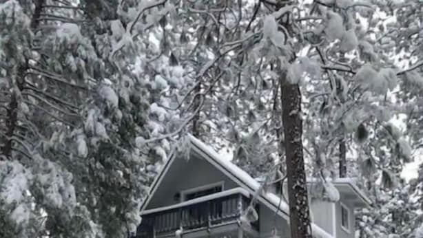 Ein zweistöckiges Haus mit Balkon, umgeben von schneebedeckten Bäumen.