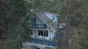 Ein zweigeschossiges Haus mit Balkon, umgeben von Bäumen.