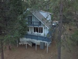 A two-story house with a balcony, surrounded by trees.