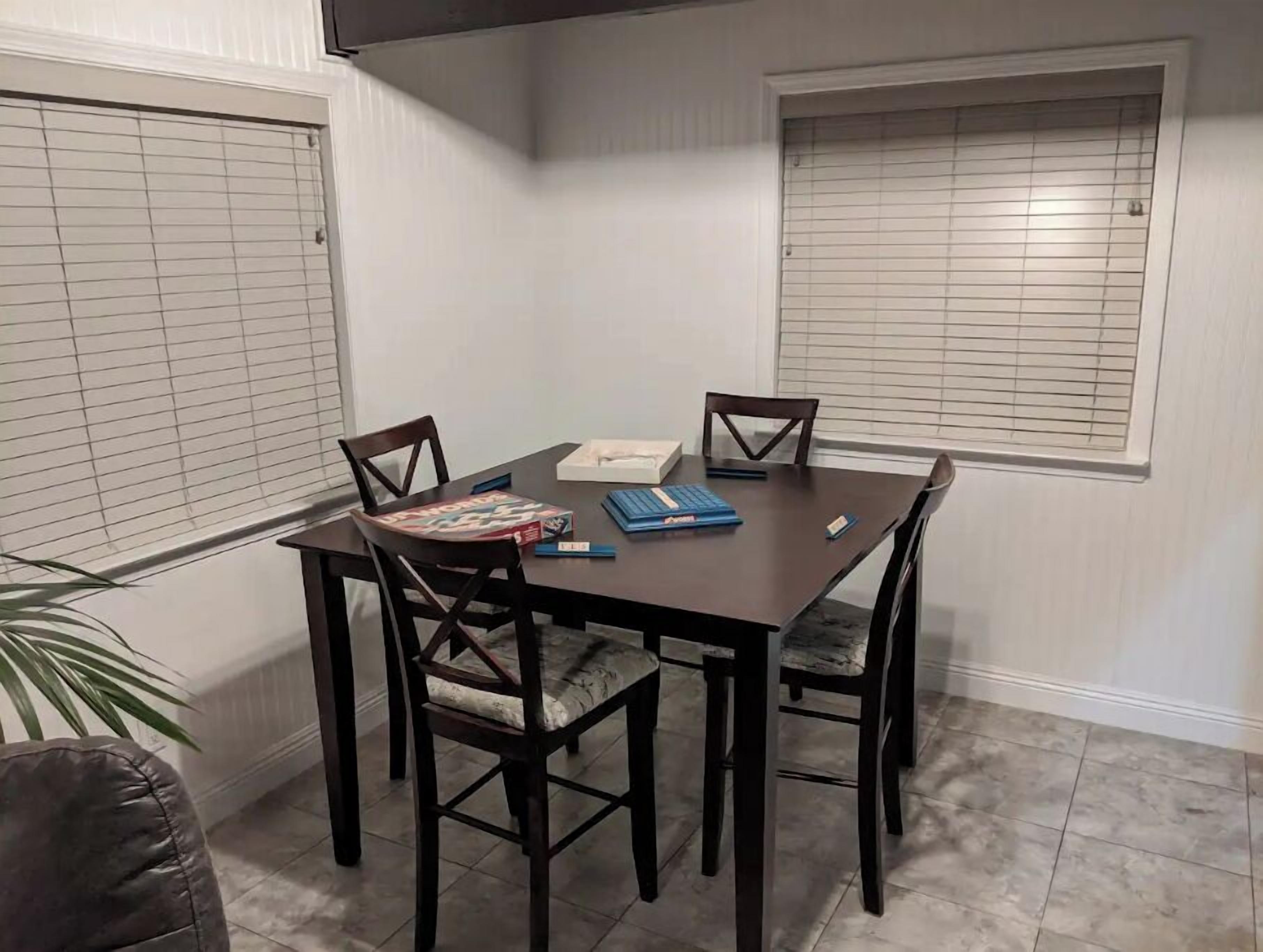A dining area with a dark wooden table, four chairs, and a window with blinds.