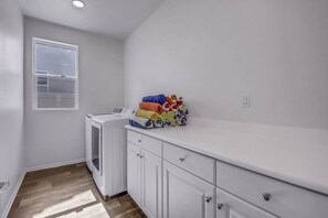 A laundry room with a washing machine, a drying rack, and neatly folded towels. - Breezin': Pool, Spa, Fire Pit, Foosball and more! (Indio)