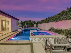 A swimming pool with a slide, lounge chairs, and a covered patio area. - Breezin': Pool, Spa, Fire Pit, Foosball and more! (Indio)