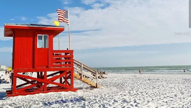 Ein roter Rettungsschwimmturm mit einer US-amerikanischen Flagge am Strand.