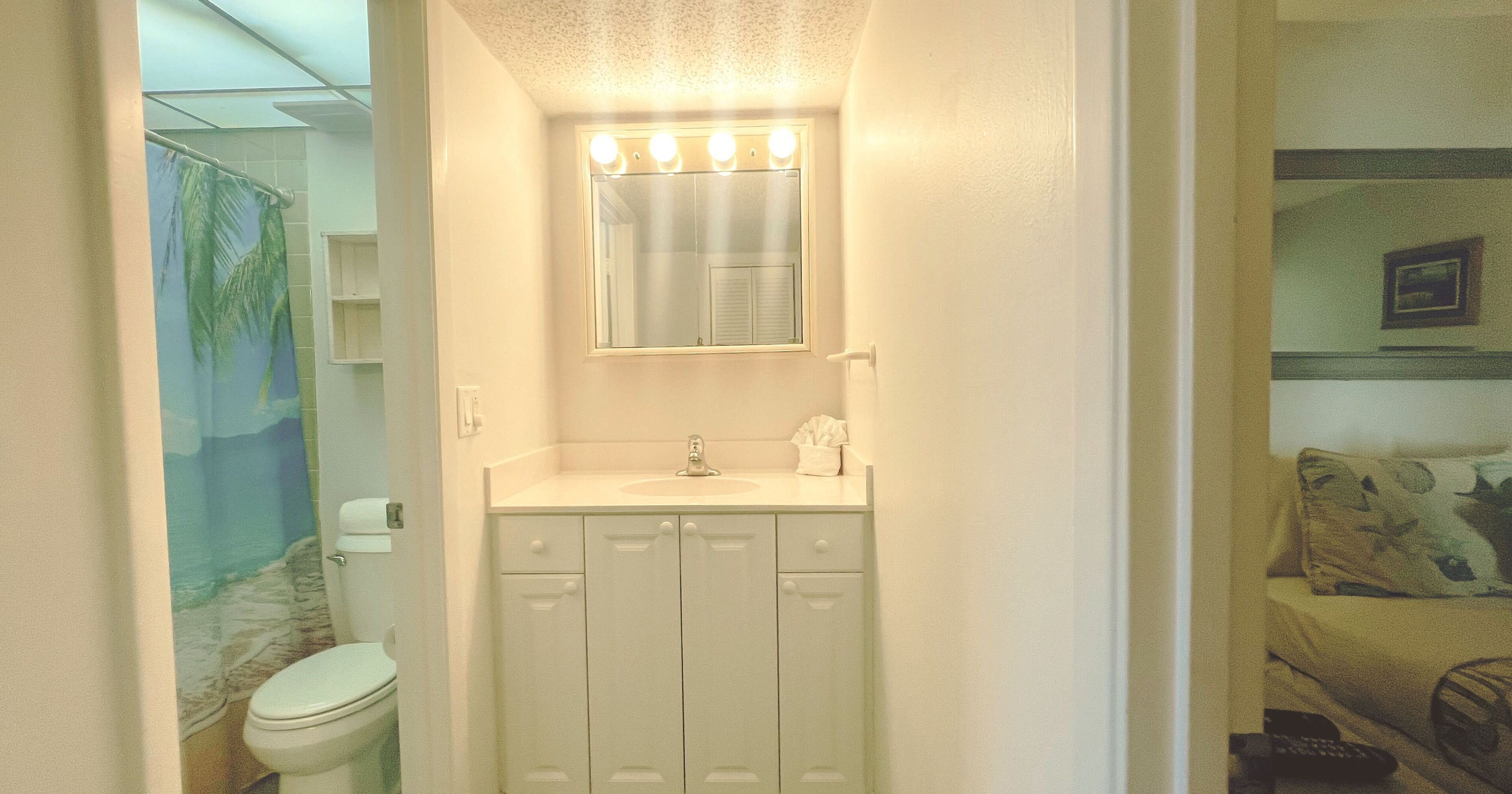 A bathroom with a toilet, sink, and mirror.