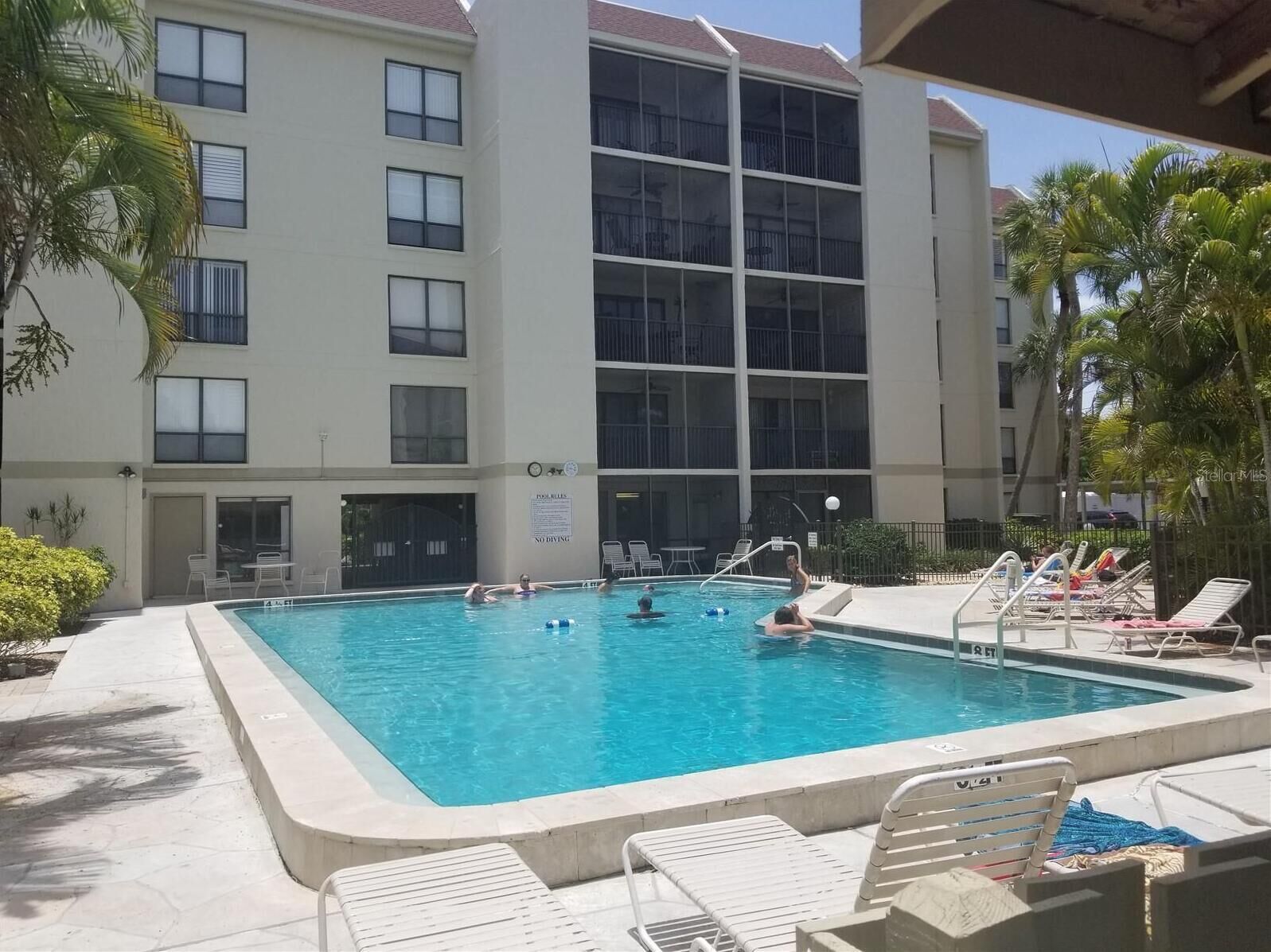 A swimming pool with lounge chairs and a building in the background.