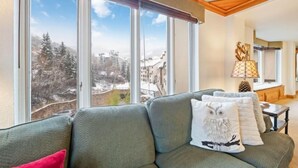 Un salon chaleureux avec une grande fenêtre donnant sur un paysage enneigé.