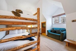 A room with a bunk bed made of natural wood, a blue sofa, and a wooden bench. - The Charter at Beaver Creek L331 (Beaver Creek)