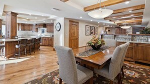 A spacious kitchen with wooden cabinets, a central island, and a dining area with chairs and a table. - The Charter at Beaver Creek L032 (Beaver Creek)