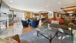 A spacious living area with a fireplace, modern furniture, and a view of the kitchen and dining area. - The Charter at Beaver Creek L032 (Beaver Creek)
