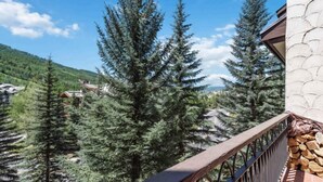 A balcony with a view of tall evergreen trees and a distant mountain range. - The Charter at Beaver Creek L011 (Beaver Creek)