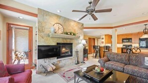 A living room with a fireplace, a sofa, a coffee table, and a TV. - The Charter at Beaver Creek A220 (Beaver Creek)