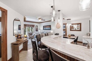 A modern kitchen with a large island, pendant lighting, and a dining area with a round table.